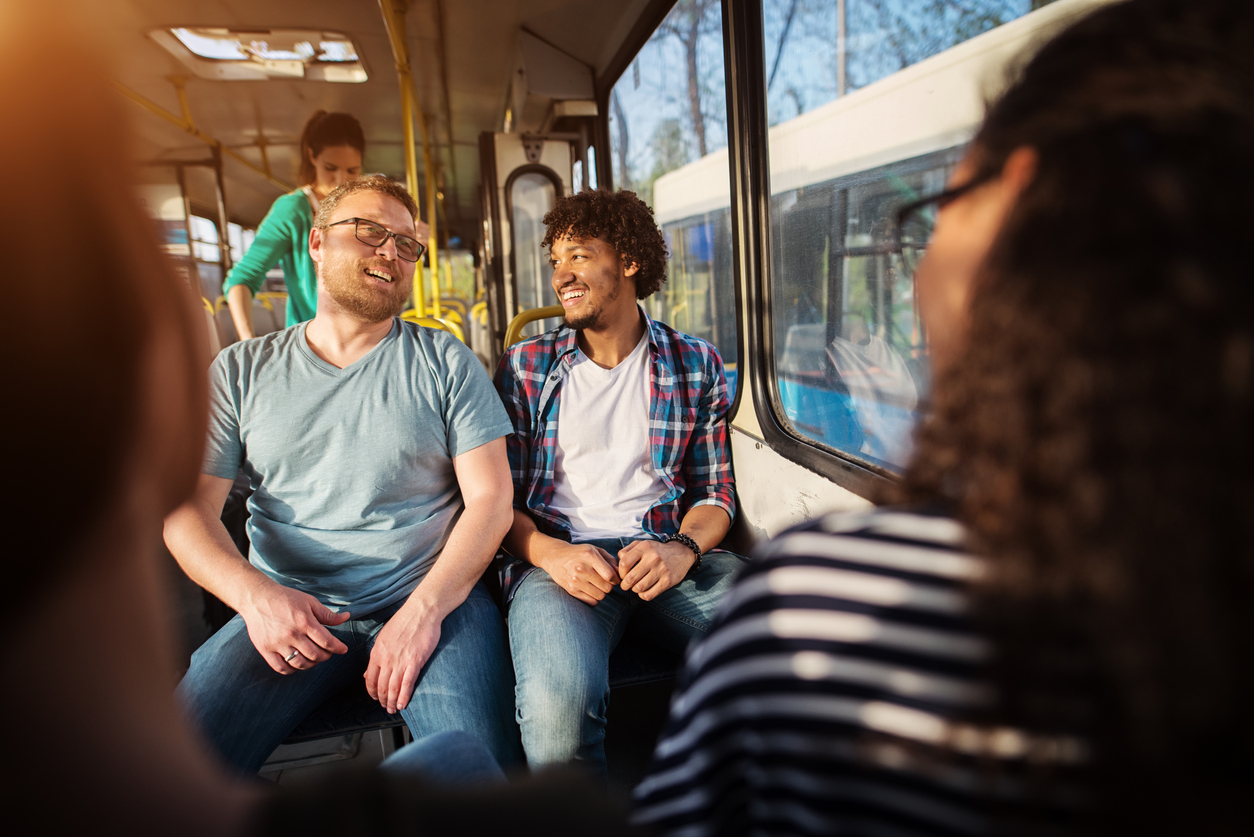 Two young handsome male friends are sitting together on a bus talking