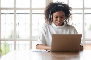 African businesswoman wearing headphones using laptop at work typing message