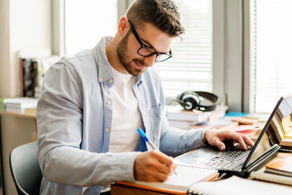 Young man in library working on laptop employee learning at computer