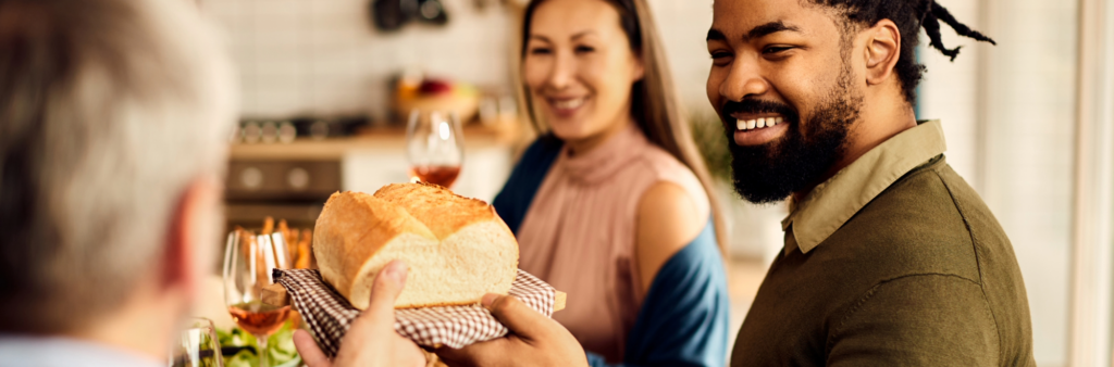 People gathered around a table passing bread, showing gratitude and goodwill.