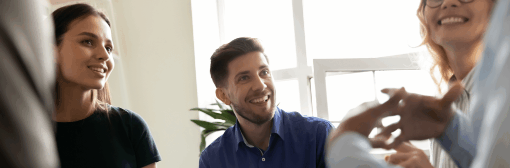 Group of colleagues smiling and receiving constructive feedback from a leader.