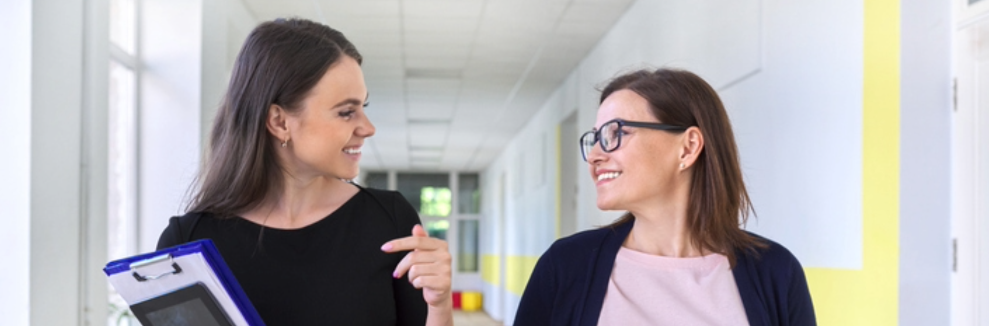 385-header-leadership-development-is-a-must-have A female leader in school hallway working to develop a fellow leader.