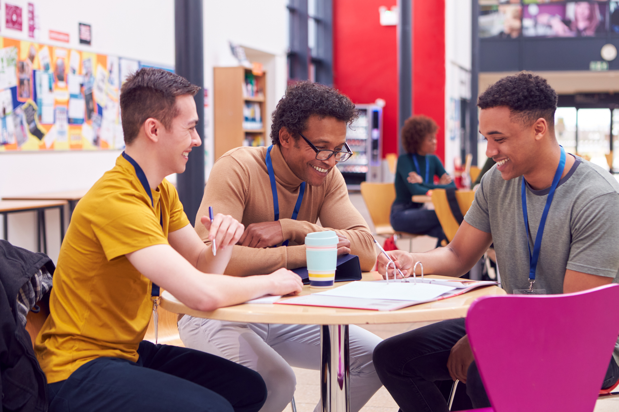College Student Meeting With Male Tutor In Busy Communal Campus Building