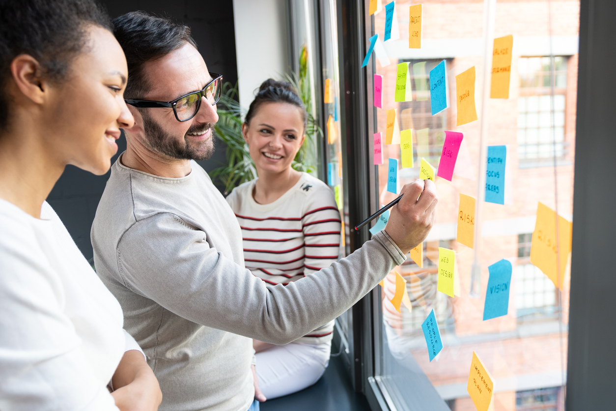 Business people meeting at office and use post it notes to share idea. Brainstorming concept. Sticky note on glass wall.